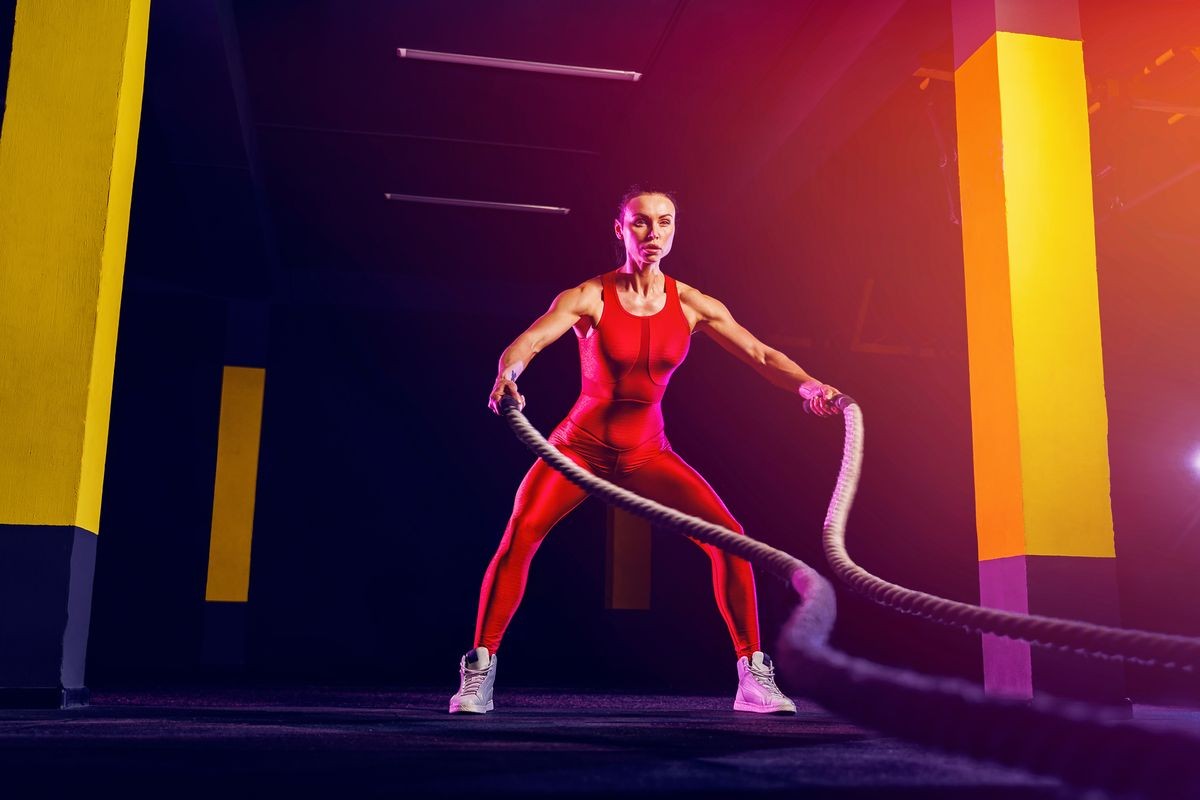 Fitness woman using training ropes for exercise at gym. Athlete working out with battle ropes at gym.